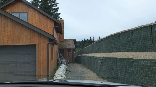 Flood barriers line the Mendenhall River, coming within inches of some homes.