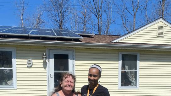 Krystal Steward, right, stands with a resident in Ann Arbor’s Bryant neighborhood who had solar panels installed on her home in 2022.